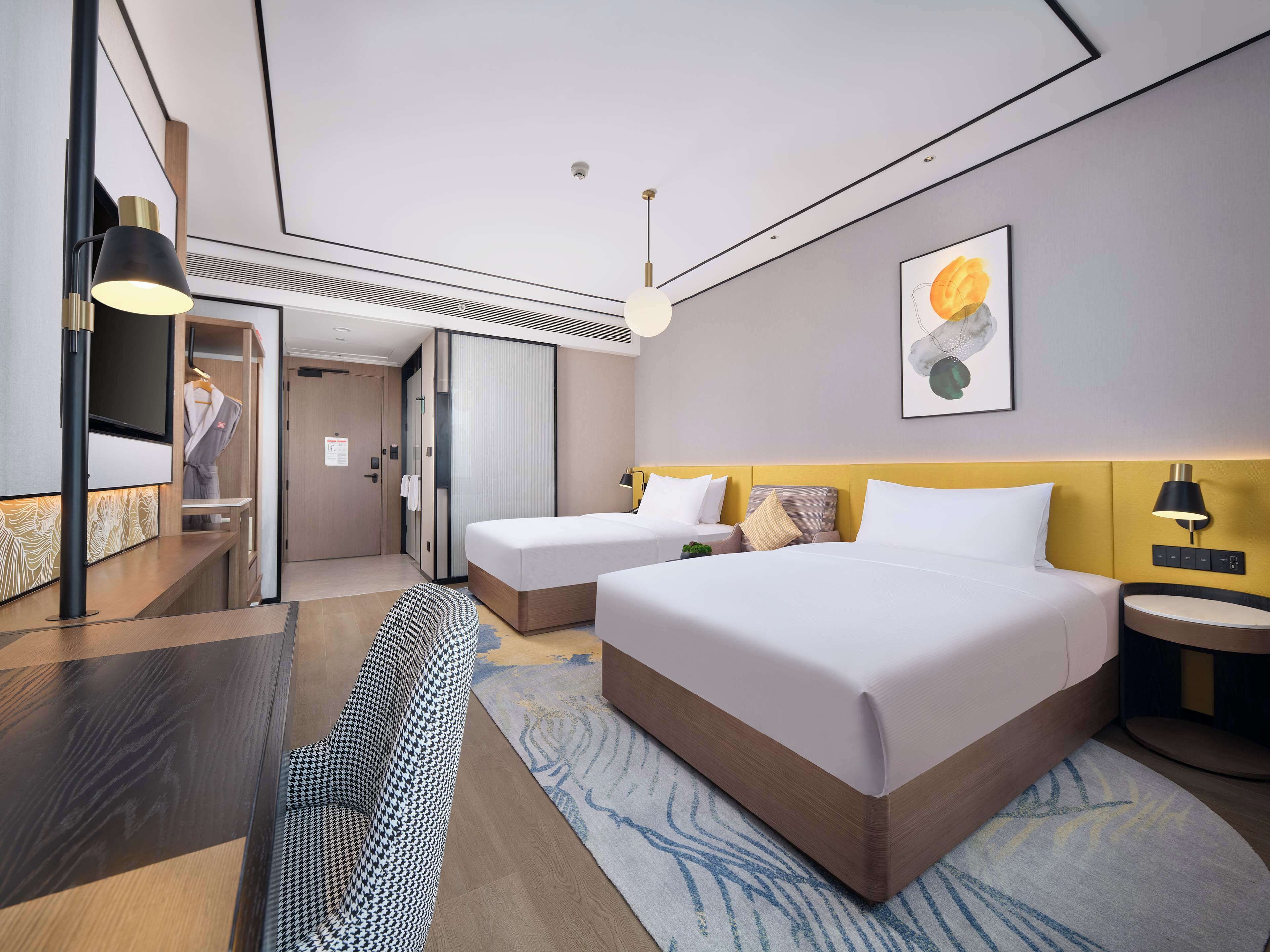 Una habitación de hotel moderna con dos camas, televisión, armario y baño.