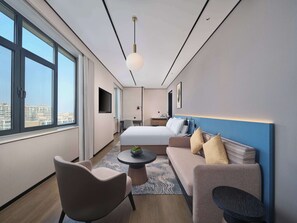 A modern hotel room with a large bed, a sofa, a desk, and a TV. - Hilton Garden Inn Ji'nan High-Tech Zone (Jinan)