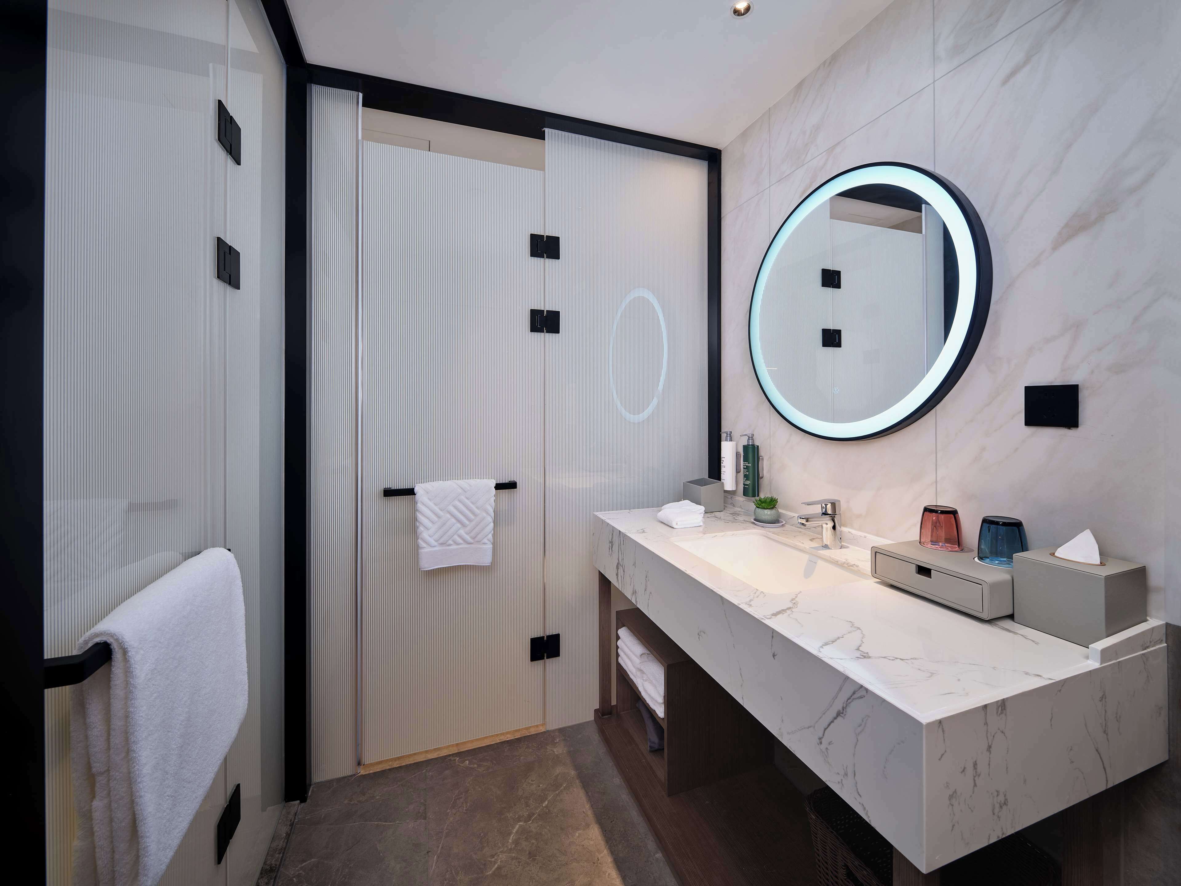 A modern bathroom with a large mirror, two sinks, and a towel rack.