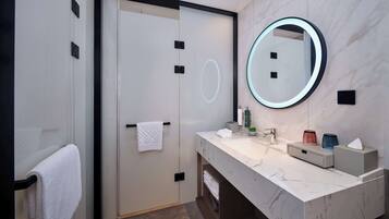 A modern bathroom with a large mirror, two sinks, and a towel rack.