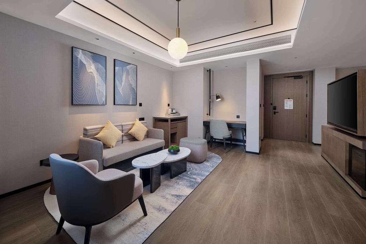 Uma sala de estar moderna com sofá, poltronas, mesa de centro, escrivaninha e televisão.