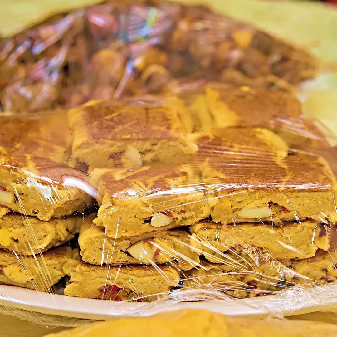A tray of layered dessert bars, possibly brownies or a similar baked good, with visible nuts and chocolate pieces.