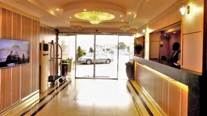A hotel lobby with a reception desk, a television, and a chandelier. - The Patron Hotel Suites Lekki (Lekki)
