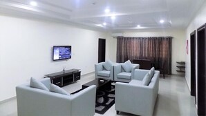 A modern living room with two sofas, a TV, and a coffee table. - The Patron Hotel Suites Lekki (Lekki)