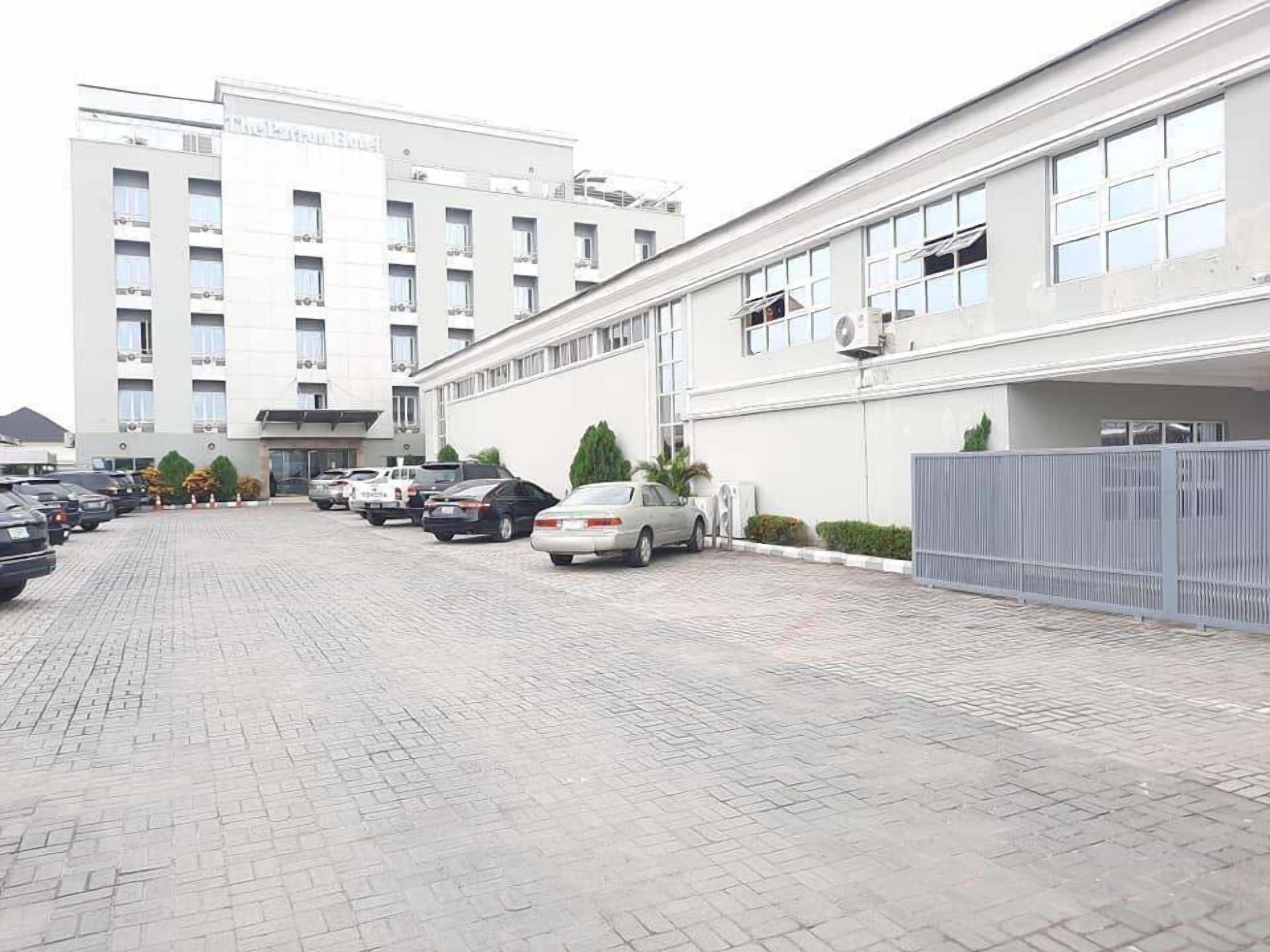 A hotel with a parking lot and a building with multiple floors and balconies.