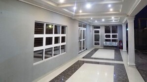 A spacious hallway with a marble floor, large windows, and a ceiling with recessed lighting. - The Patron Hotel Suites Lekki (Lekki)