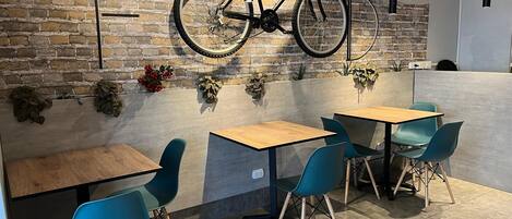 A modern cafe with a brick wall, wooden tables, and teal chairs.