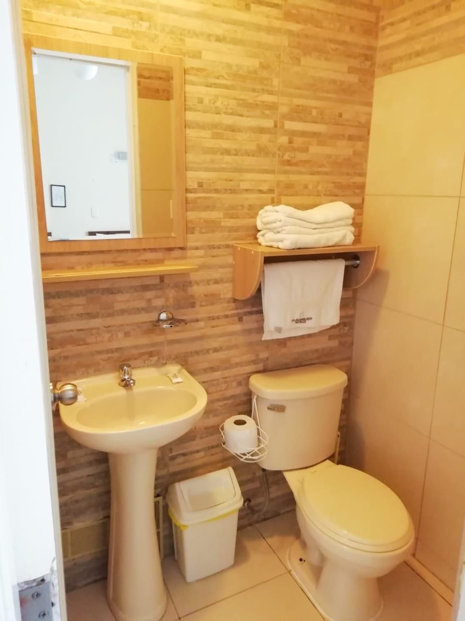 A bathroom with a wooden wall, a sink, a toilet, and a towel rack.
