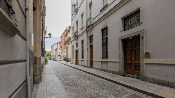A cobblestone street lined with historic buildings, featuring a mix of architectural styles and a quiet, pedestrian-friendly atmosphere. - Il Colibrì by Wonderful Italy (Turin)