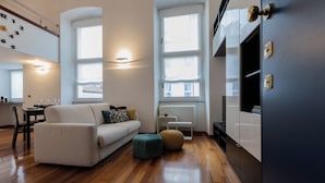 A modern living room with a sofa, ottoman, and a dining area with chairs and a table. - Il Colibrì by Wonderful Italy (Turin)