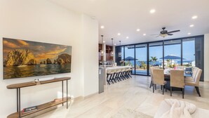 Een moderne woonkamer met een groot schilderij, een eetgedeelte met uitzicht en een keuken met een bar.