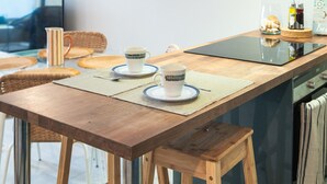 A modern kitchen with a wooden table, stools, and a built-in stove. - Costa del Silencio: Private Terrace & Pool (Arona)