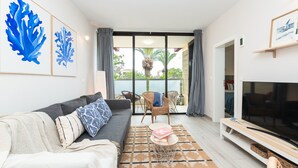 A modern living room with a sofa, a TV, and a view to the outside. - Costa del Silencio: Private Terrace & Pool (Arona)