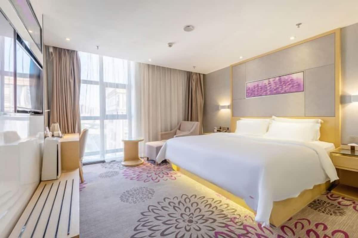A modern hotel room with a large bed, a desk, and a chair.