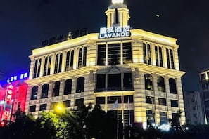 Un hôtel reconnaissable à son enseigne bien visible, sur laquelle on peut lire « LAVANDE », et qui présente un style architectural classique, avec de nombreuses fenêtres et une tour centrale.