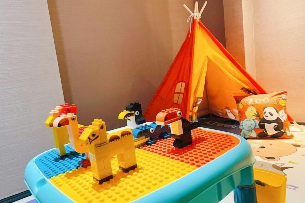 A children's play area with a blue play mat, a red and yellow tent, and various animal figures.