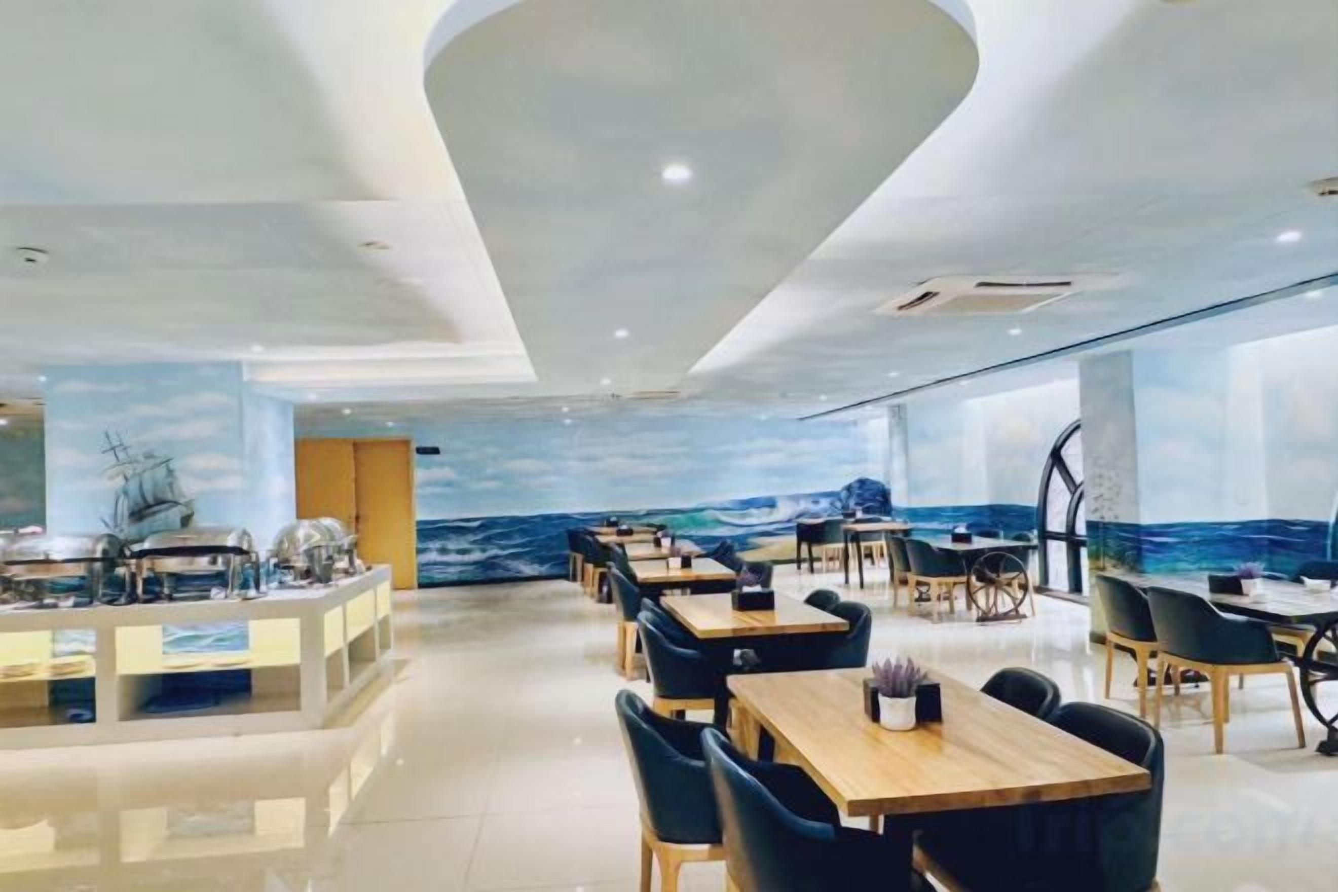 Restaurante moderno com mural temático náutico, mesas de madeira e cadeiras pretas.