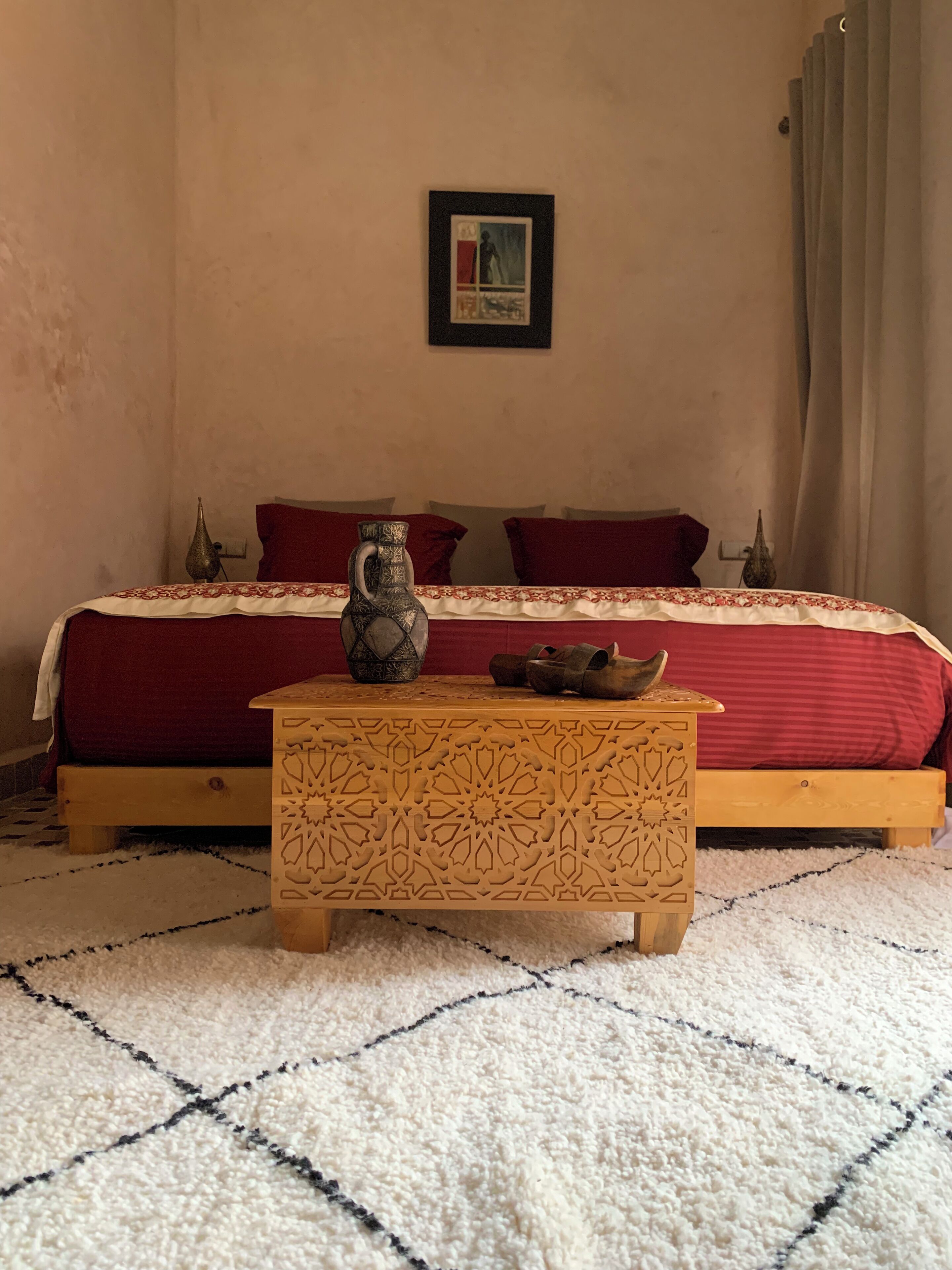 Un dormitori amb un llit, un ramader decoratiu i una taula amb un disseny.