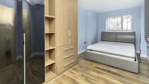 A bedroom with a bed, a wardrobe, and a window. - Cosy Feltham Apartment With 2 Bedrooms (Feltham)