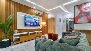 Un soggiorno moderno con una grande TV a schermo piatto, un divano verde e una parete d'accento in legno.