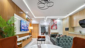 Un soggiorno moderno con un tavolo in marmo, un divano verde e una TV a parete.