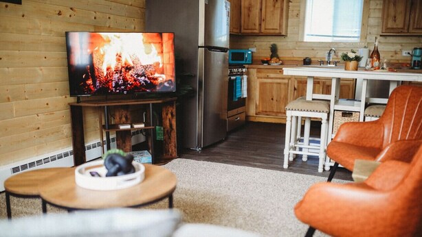 Ein gemütliches Wohnzimmer mit Fernseher, einer Holzwand, einem Kühlschrank und einer Küchenzeile mit Holzausstattung und Spüle.