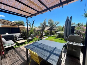 Eine Außenpatio mit Tisch, Stühlen, einem Grill und einem überdachten Sitzbereich.