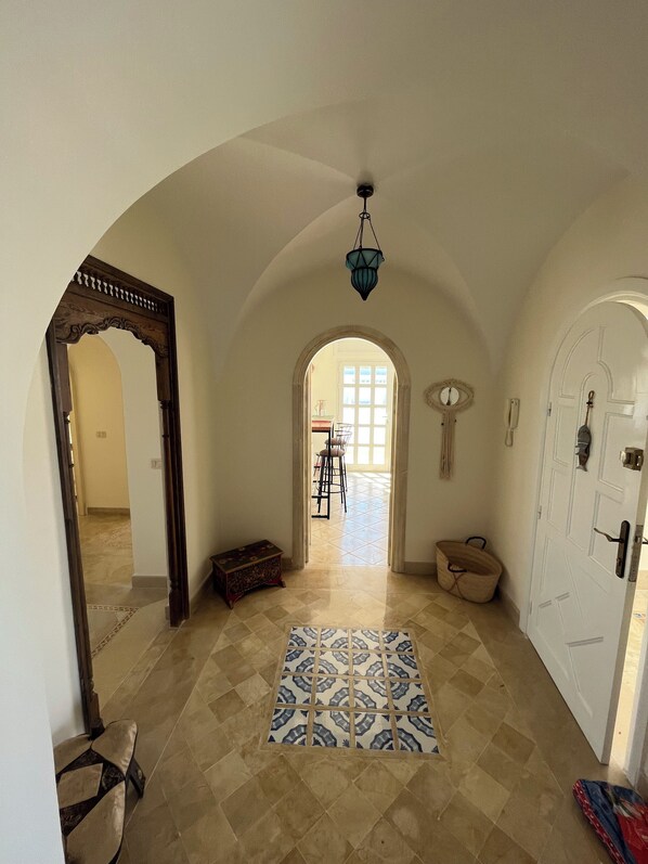 A hallway with a patterned rug, a wooden bench, and a door with a keyhole.
