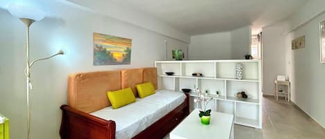 A modern living room with a wooden sofa, a white coffee table, and a white shelving unit.