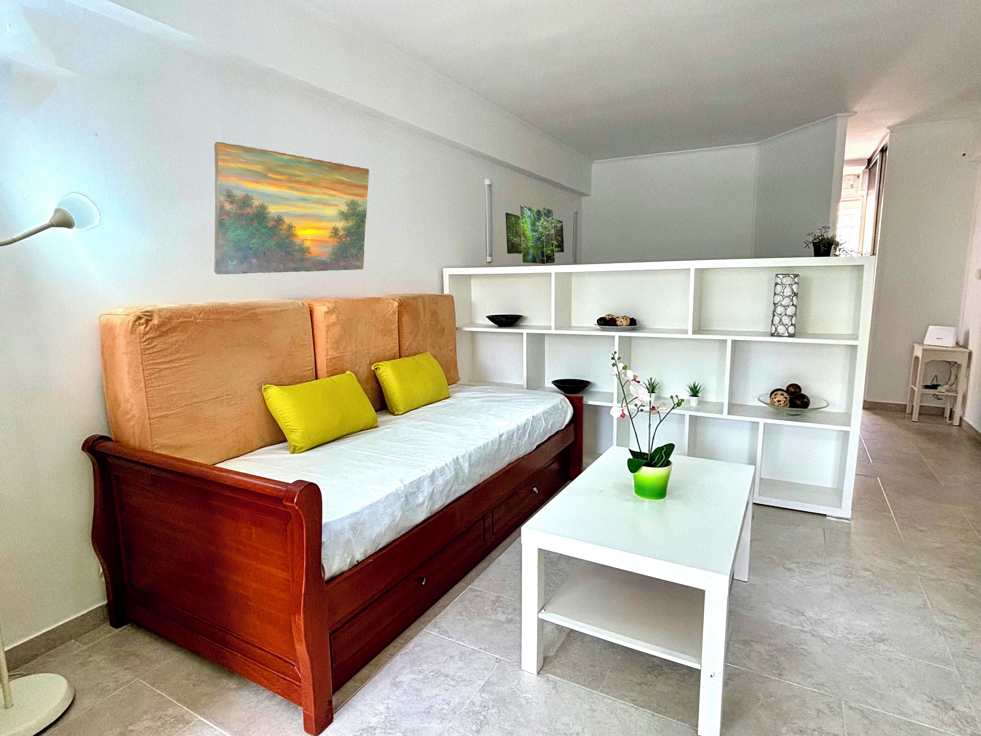 Een moderne woonkamer met een houten bank, een witte salontafel en een witte boekenkast.