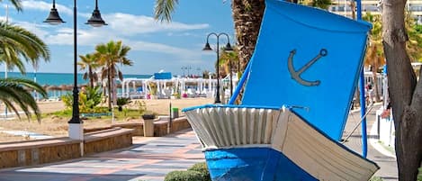 A blue boat sculpture with an anchor on a paved walkway.