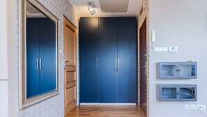 A hallway with a wooden floor, a blue wardrobe, and a mirror on the left. - Kraków Castle View - Spacious Apartment - by Rentujemy (Kraków)