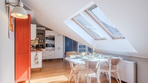 A modern kitchen with white cabinets, a wooden countertop, and a skylight above the dining area. - Kraków Castle View - Spacious Apartment - by Rentujemy (Kraków)