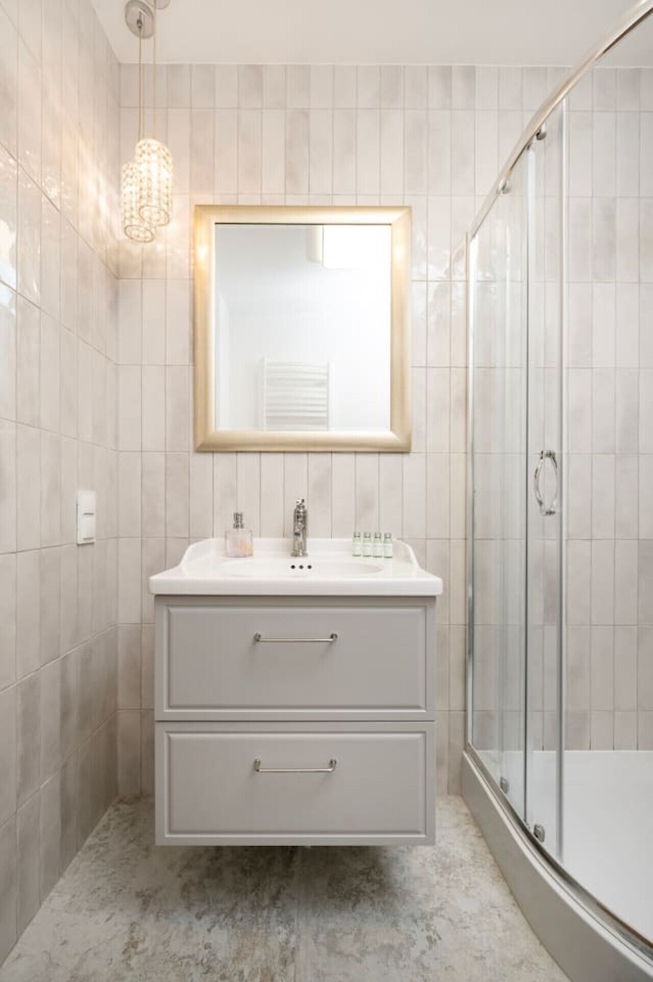 A modern bathroom with a white vanity, a glass shower enclosure, and a pendant light.