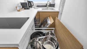 Une cuisine moderne avec des meubles blancs, un lave-vaisselle intégré et une vue sur la ville.