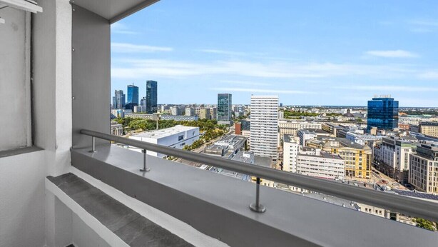 Une vue sur le paysage urbain, prise depuis un balcon doté d’une rambarde en métal.