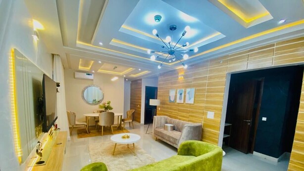 A modern living room with a green sofa, a round coffee table, and a TV on a wooden cabinet.