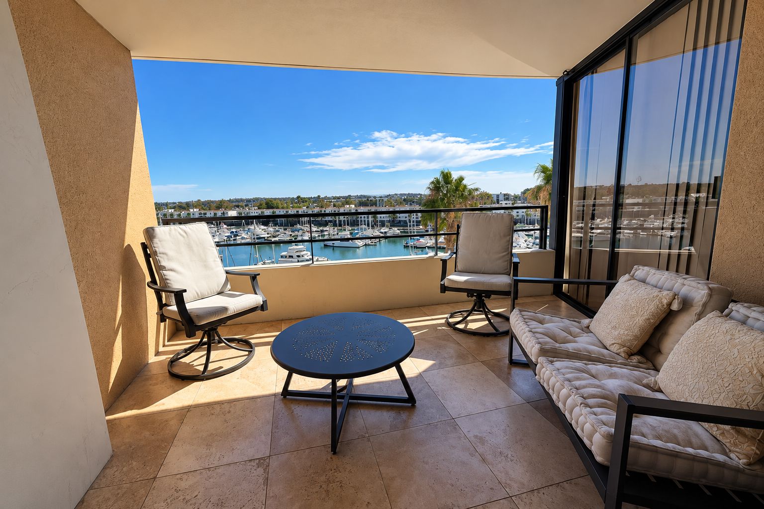 Un balcon donnant sur une marina, une table ronde, deux chaises et un canapé.