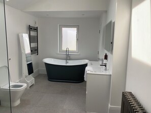 A modern bathroom with a freestanding bathtub, a toilet, and a sink. - House - Sleeps 14 - Pets Ok - Parking - Garden (Folkestone)