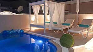 Uma área de piscina com hidromassagem, espreguiçadeiras e uma cobertura.