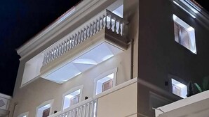 Um edifício de vários andares com uma varanda no segundo andar, janelas amplas no andar superior e um telhado plano.