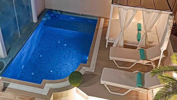 Piscina com espreguiçadeiras e toldo.
