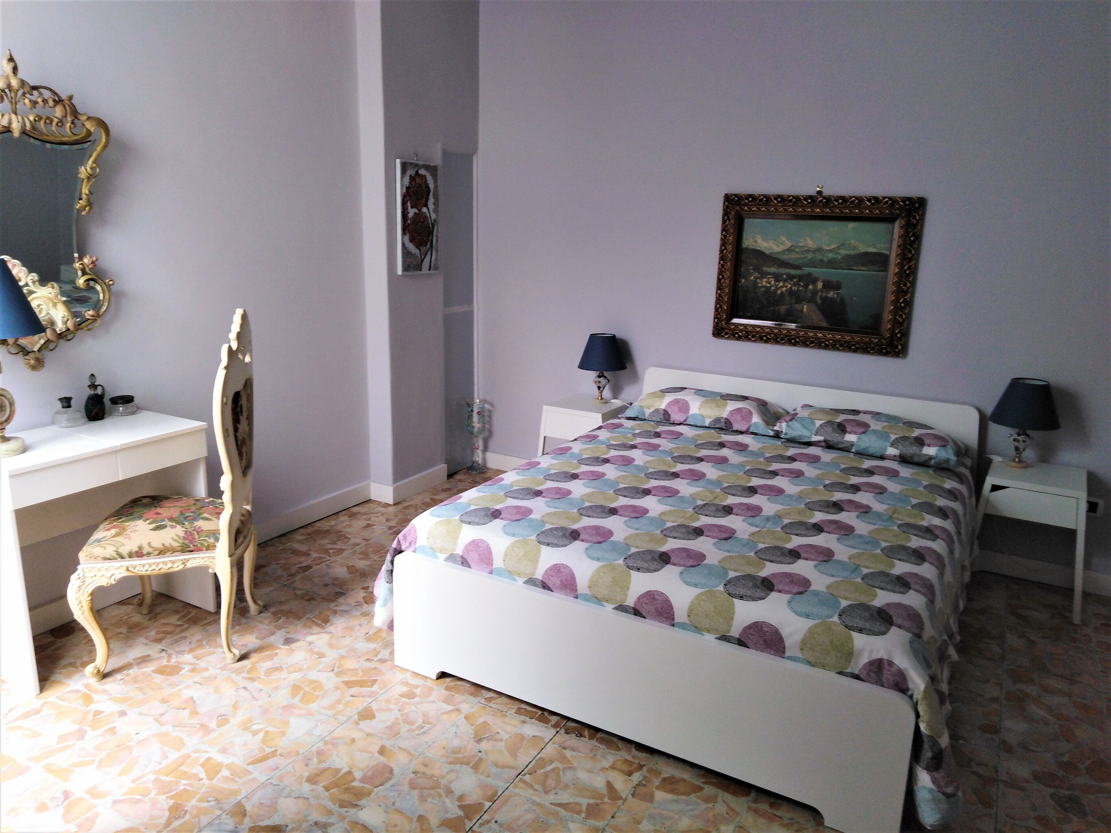 A bedroom with a bed, a desk, a chair, and a dresser.
