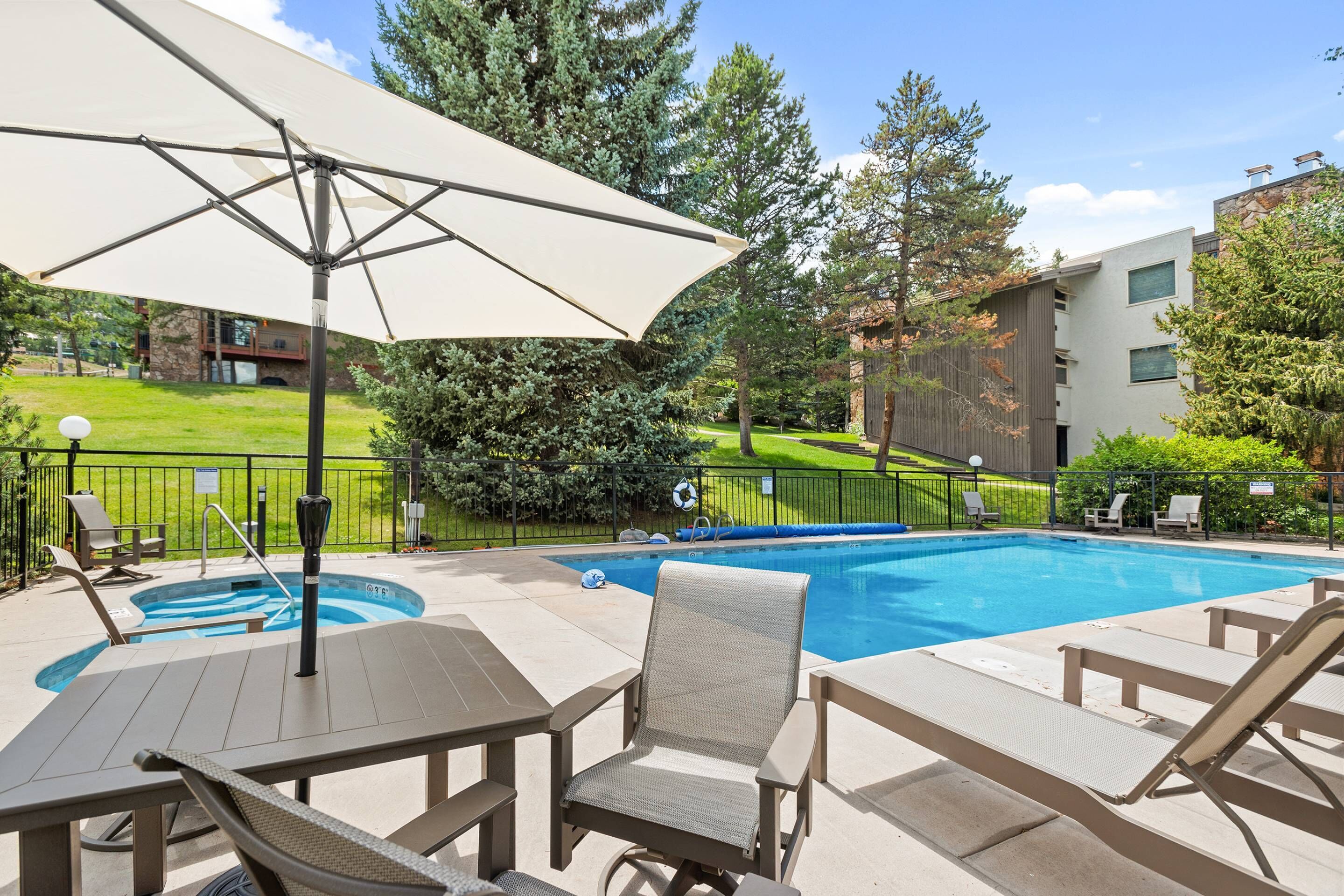 Un espace aménagé au bord de la piscine, avec des chaises longues, une table et un grand parasol.