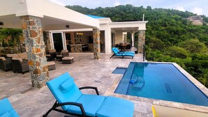A modern outdoor pool area with lounge chairs and a stone pillar structure. - BEACHFRONT 5 BEDROOM VILLA–POOL, SOLAR, PRIVATE (East End)