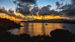 A sunset over a calm body of water with boats and distant hills. - BEACHFRONT 5 BEDROOM VILLA–POOL, SOLAR, PRIVATE (East End)