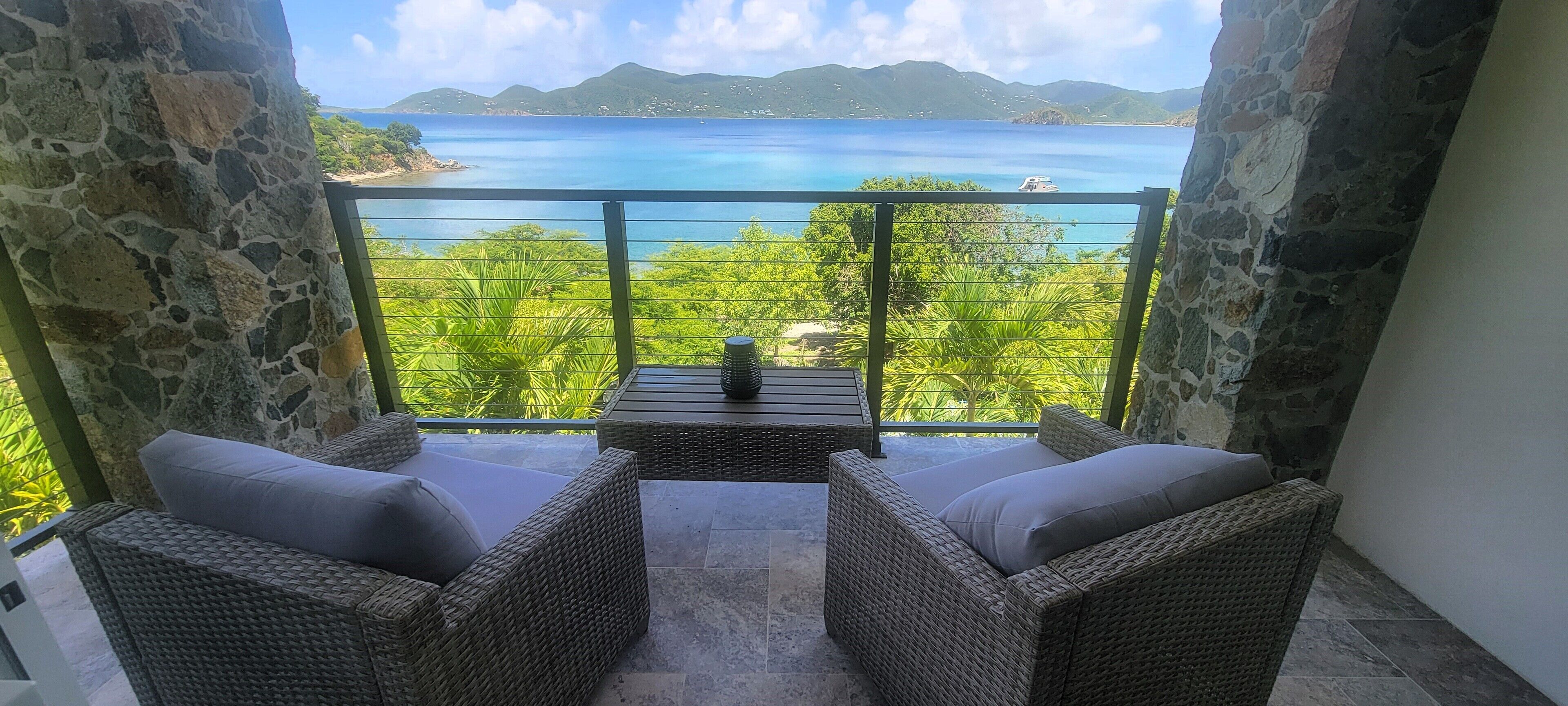 Ein Balkon mit Korbmöbeln und Blick auf das Meer.