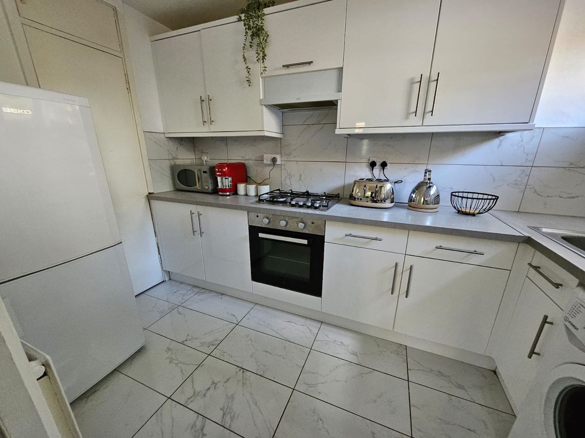 A kitchen with white cabinets, a gas stove, a microwave, and a washing machine.