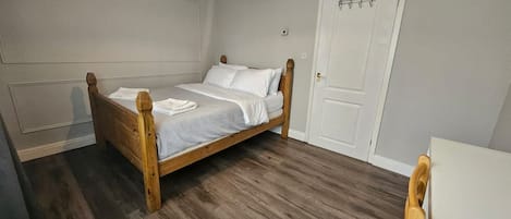 A bedroom with a wooden bed, a white door, and a wooden chair.