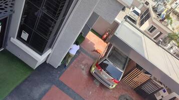 A residential area with a parked car, a person walking, and a building with a window and a door.